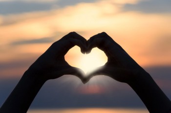 hands creating a heart and sunset