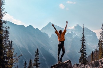 Woman jumping and looking at the wonderful views of mountains in Canada