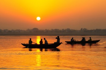 Personas de India navegan por el río al atardecer
