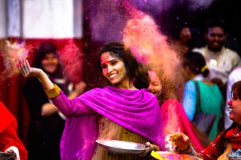 Mujer india arroja polvos de colores en Holi India