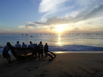 Personas  acarrean un barco a la orilla en las playas de Sri Lanka