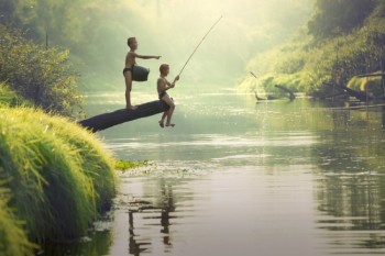 Dos niños camboyanos juegan a pescar con caña en un río