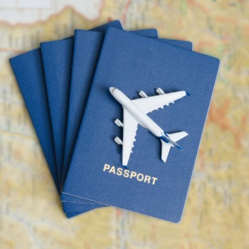 Avión de juguete sobre pasaportes azules apoyados en un mapa