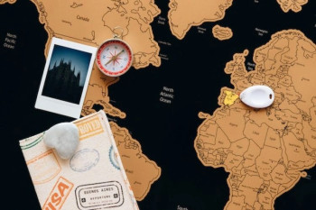 Passaporto con timbri su una mappa del mondo accanto a una bussola