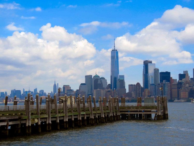 Skyline di Lower Manhattan con il One World Trade Center e un molo in primo piano.
