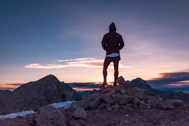 Alpinista in piedi sulla cima di una montagna che contempla l'alba sull'Himalaya