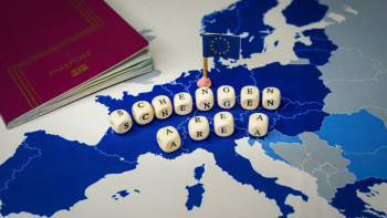 Mappa dello spazio Schengen con un passaporto rosso, la bandiera dell'Unione europea e dadi di legno che formano le parole Schengen Area