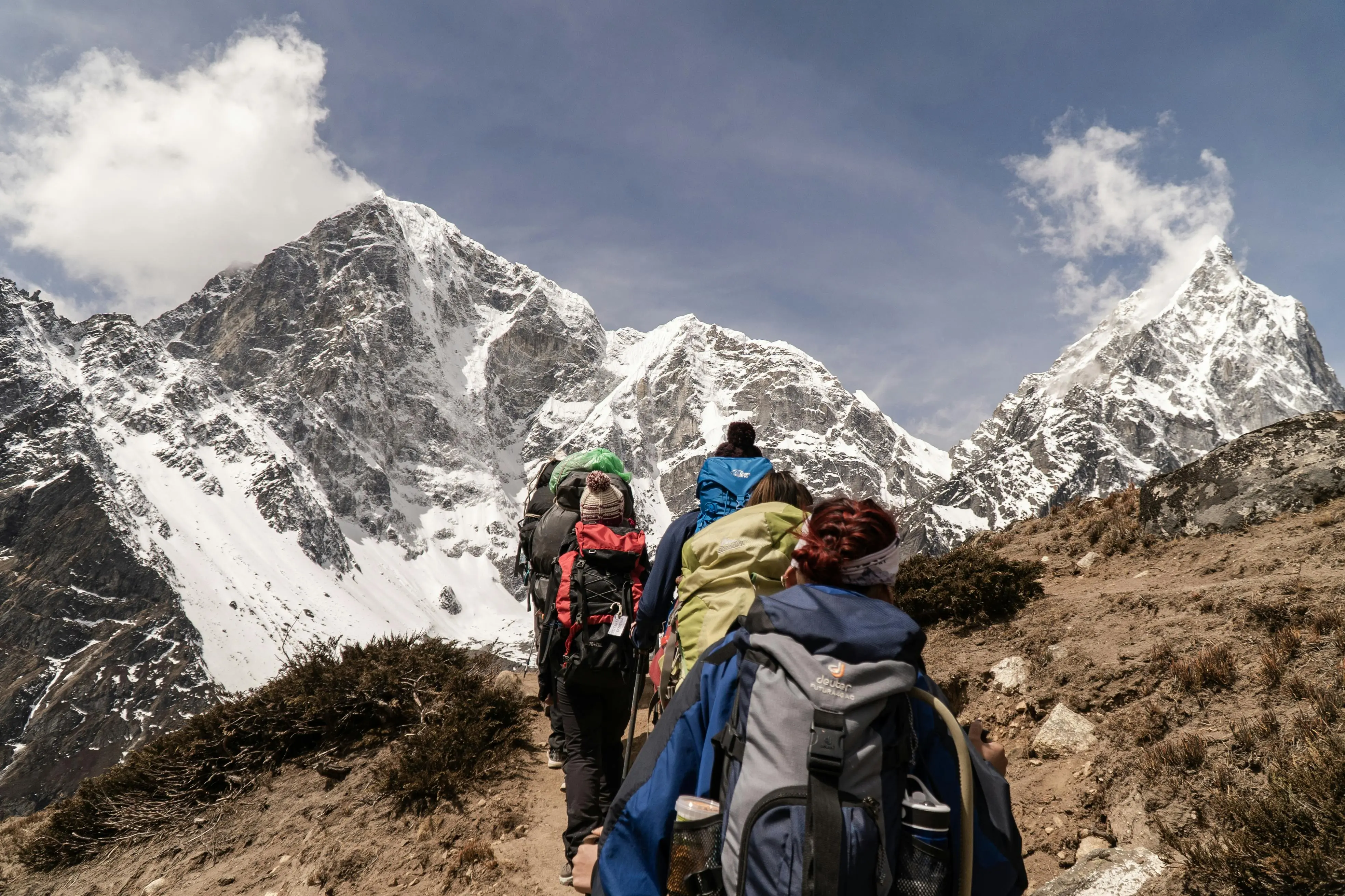 Trekkers equipados en ruta por el Himalaya nepalés con montañas nevadas al fondo