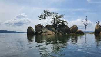 Visto Costa d'Avorio: isolotto roccioso con alberi tropicali riflessi in un lago tranquillo