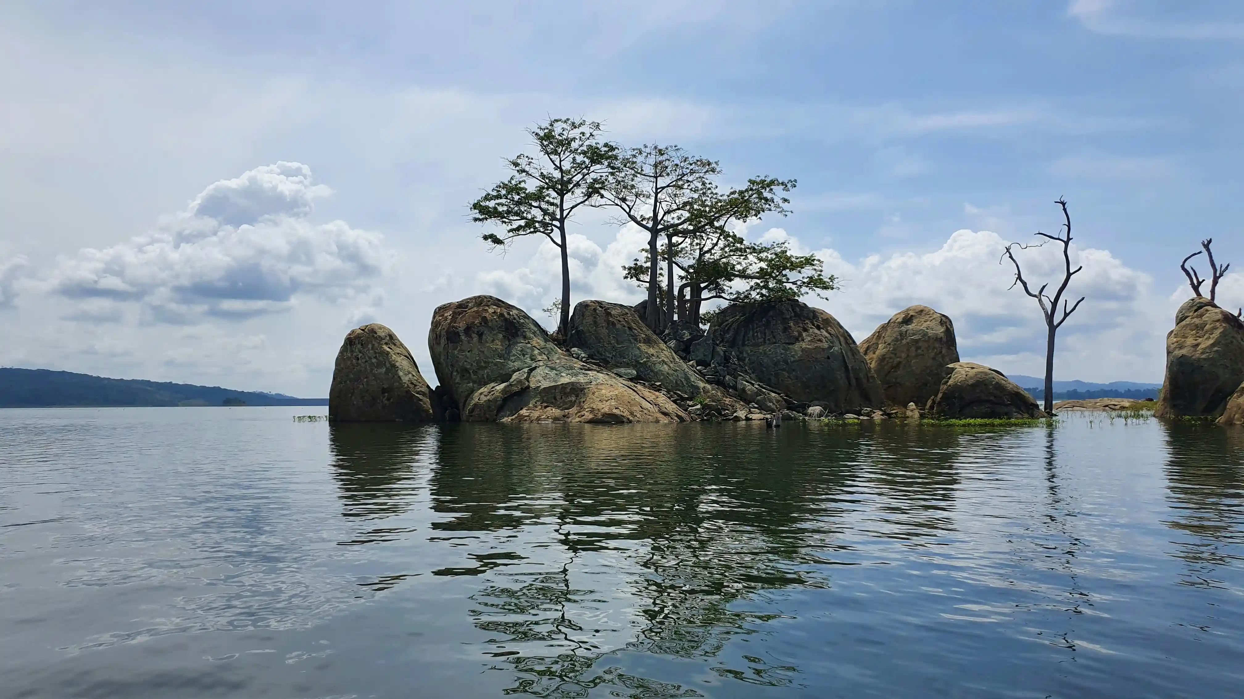 Visto Costa do Marfim: ilhota rochosa com árvores tropicais refletidas em um lago tranquilo
