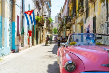 Auto d'epoca rosa in una strada colorata dell'Avana, Cuba