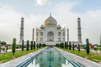 Vista frontale del Taj Mahal riflesso nel canale centrale dei giardini di Agra, India