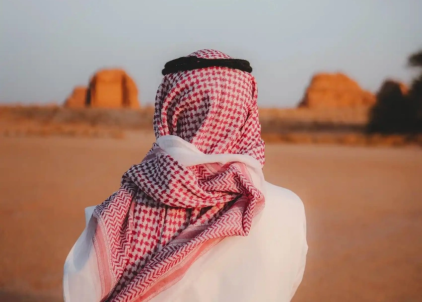 Persona in abito tradizionale arabo che contempla il deserto dell'Arabia Saudita