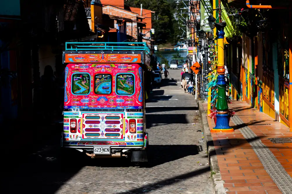 Traditional Jeep driving through a colorful street in Colombia